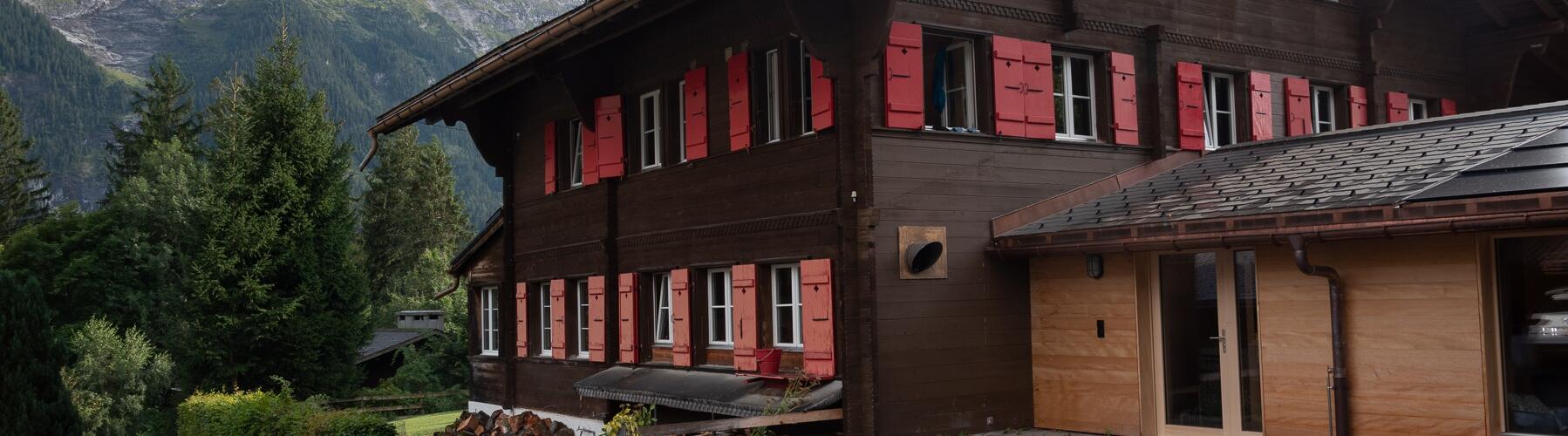 ein großes braunes Haus mit roten Fensterläden