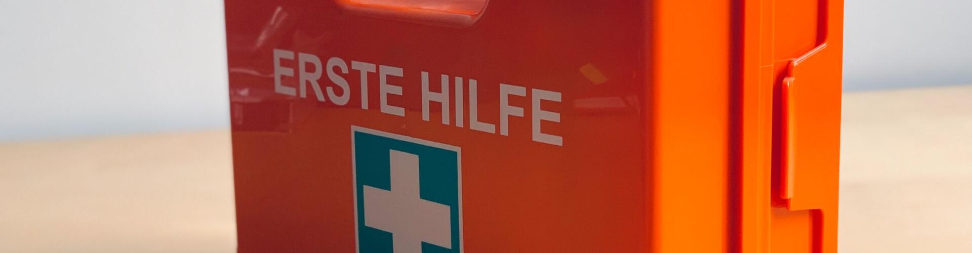 eine kleine orangefarbene Notfalldose mit einem weißen Kreuz darauf