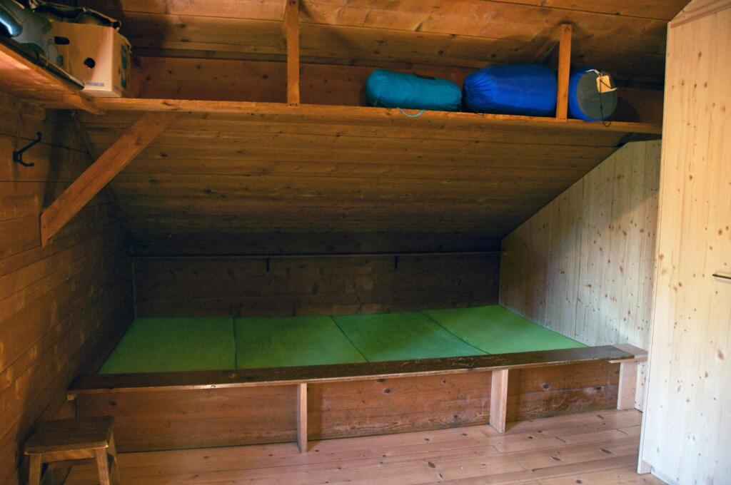 un lit avec des coussins verts dans une chambre en bois 