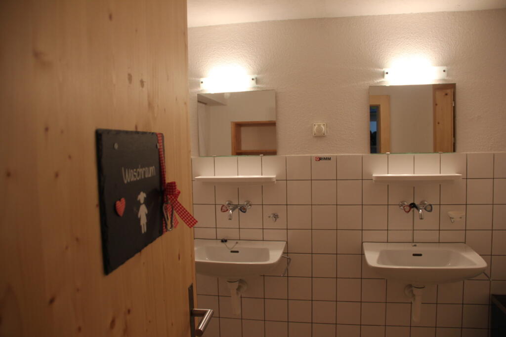 une salle de bains avec des carreaux blancs et une rangée de lavabos 