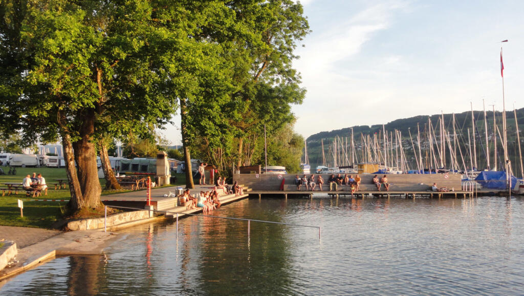 un groupe de personnes assises sur un quai près d'un plan d'eau 