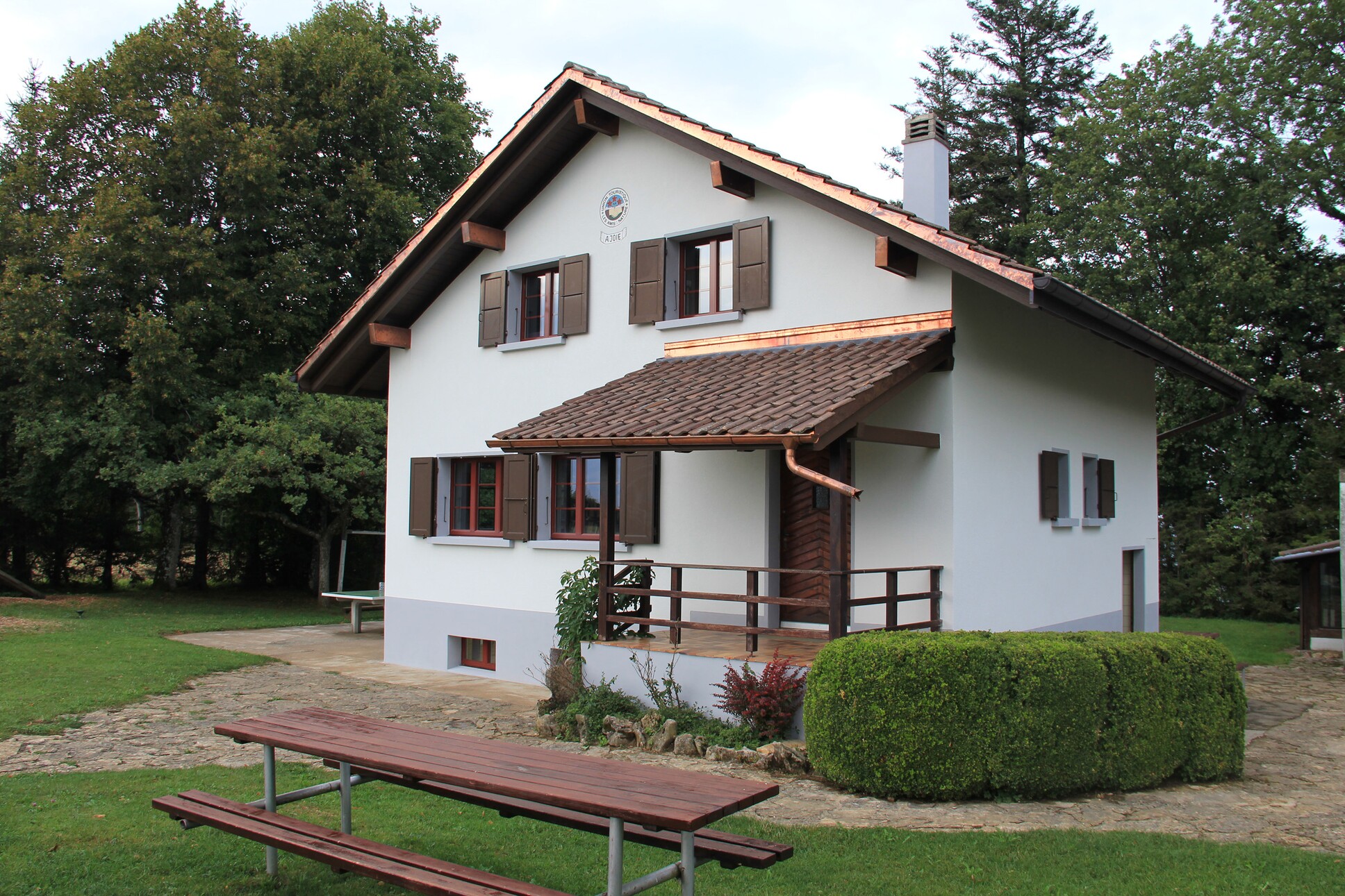 ein weißes Haus mit einem braunen Dach und einer Holzbank