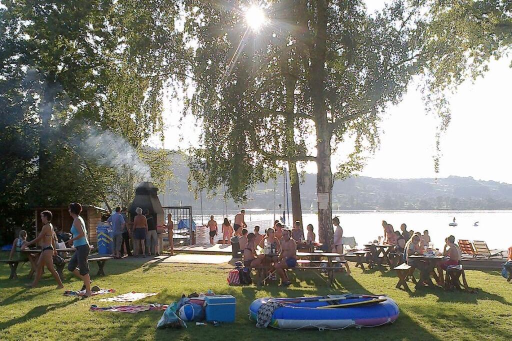 un groupe de personnes assises sur l'herbe près d'un lac 
